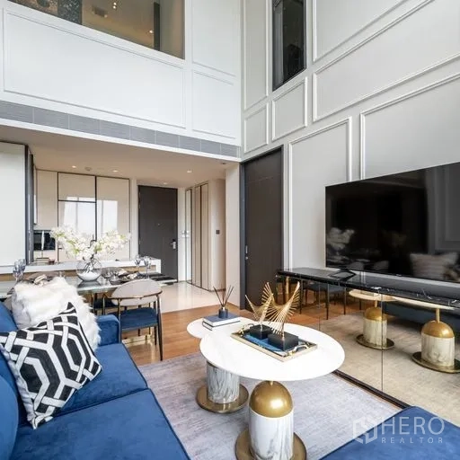 คอนโด ให้เช่าในKhlong Toei, Bangkok - ห้องนั่งเล่นสไตล์โมเดิร์น โซฟาสีน้ำเงิน โต๊ะกลางคู่ ตู้ทีวีขนาดใหญ่ ผนังบัวสูง และหน้าต่างกระจกเต็มบาน