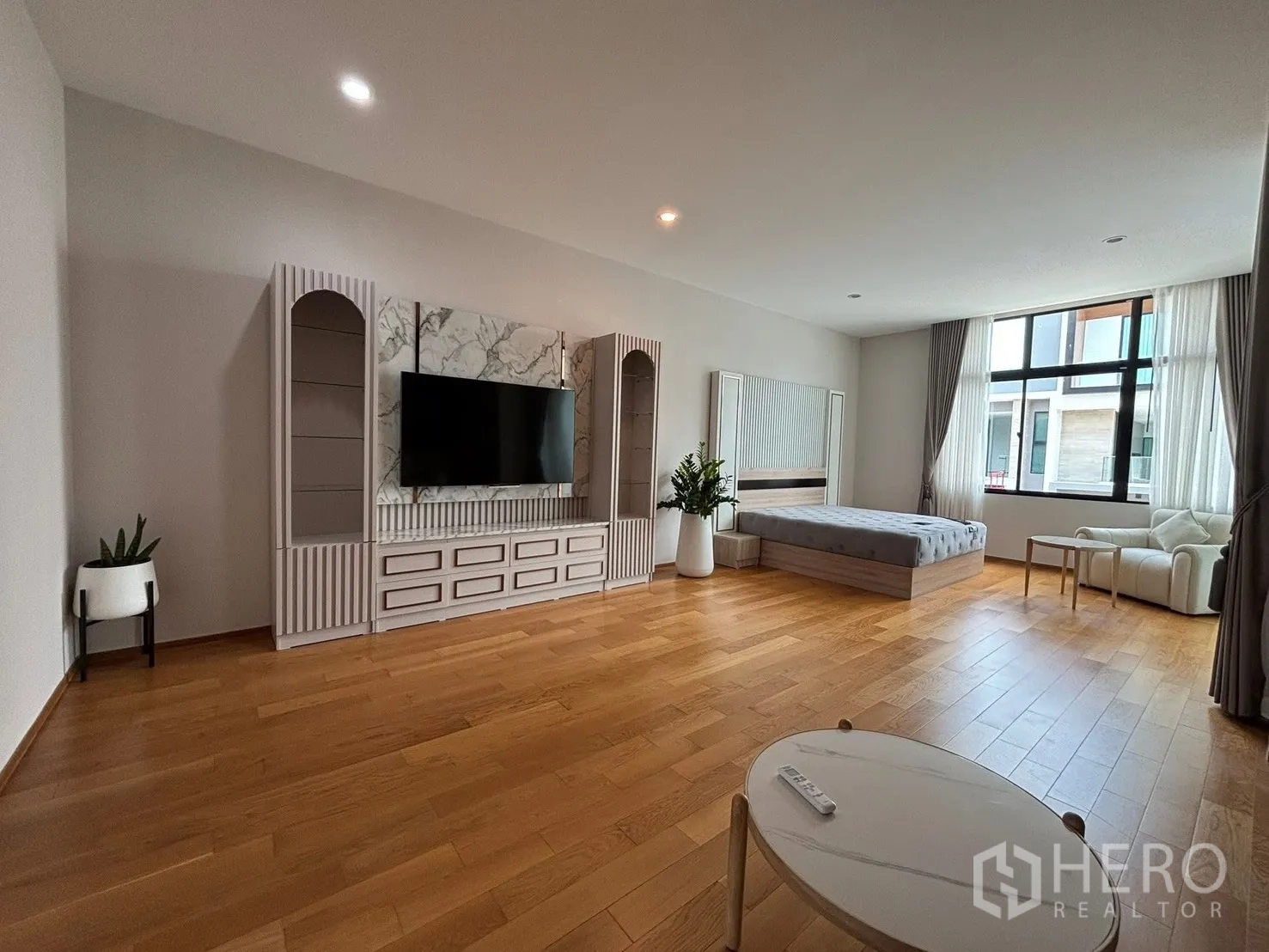 Townhouse for rent in Saphan Sung, Bangkok - Large open room with bed, television cabinet, and seating by the window.