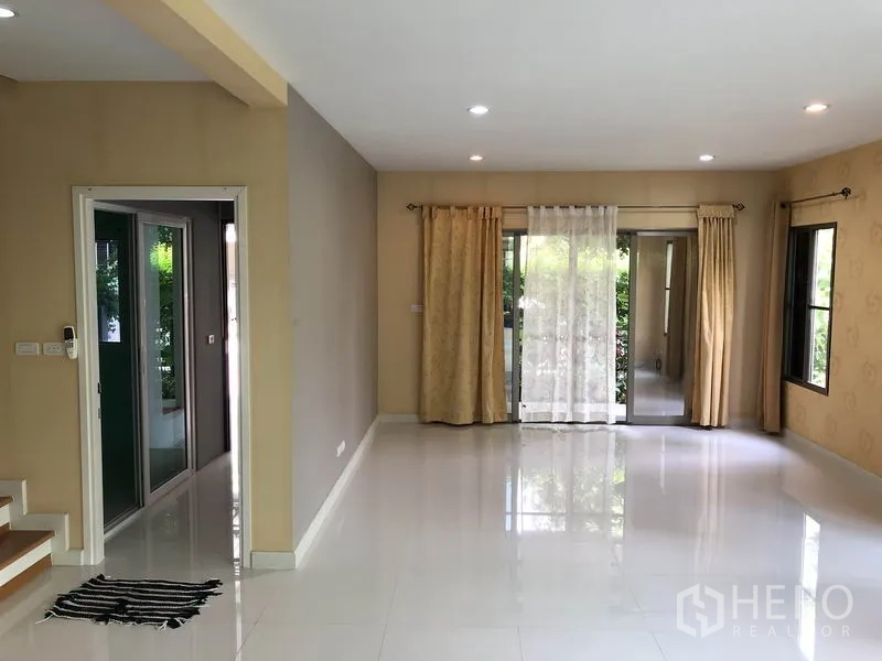 บ้าน ให้เช่าในSuan Luang, Bangkok - ห้องนั่งเล่นโปร่งสว่าง พื้นกระเบื้องเงา ไฟดาวน์ไลท์ และประตูกระจกบานเลื่อนออกสวน