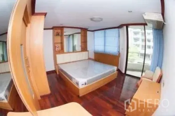 Condominium for sale in Watthana, Bangkok - Bright bedroom with built-in wardrobe, wood floors and access to a balcony view.
