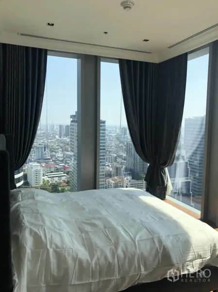 公寓 出租在Bang Rak, Bangkok - 卧室配转角落地窗与深色窗帘，俯瞰曼谷天际线。