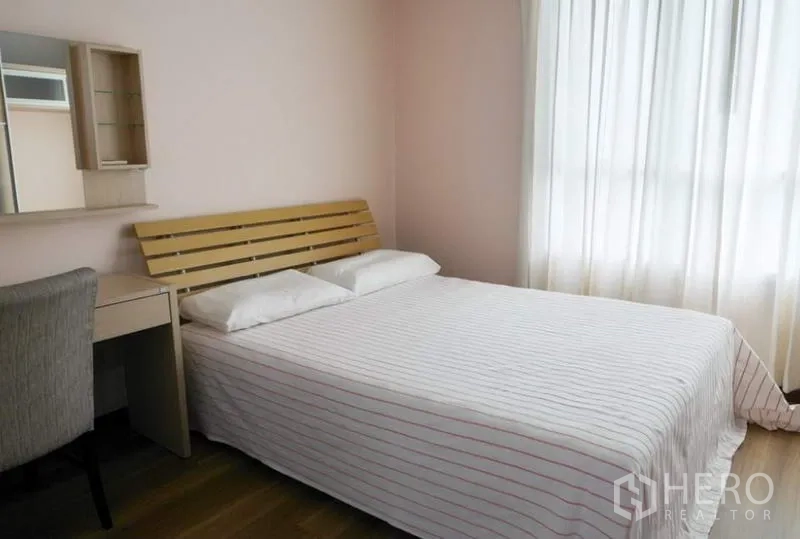 Condominium for rent in Pathum Wan, Bangkok - Second bedroom with desk, wall mirror and large window with sheer curtains providing natural light.