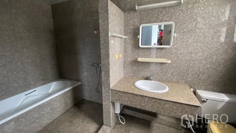 联排别墅 出租在Bang Na, Bangkok - 浴室配浴缸、石纹墙面与长台面洗手盆。