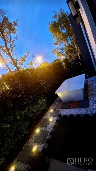 Detached House for rent in Bang Bo, Samut Prakan - Garden at dusk with pathway lighting and a freestanding outdoor tub next to the hedge.