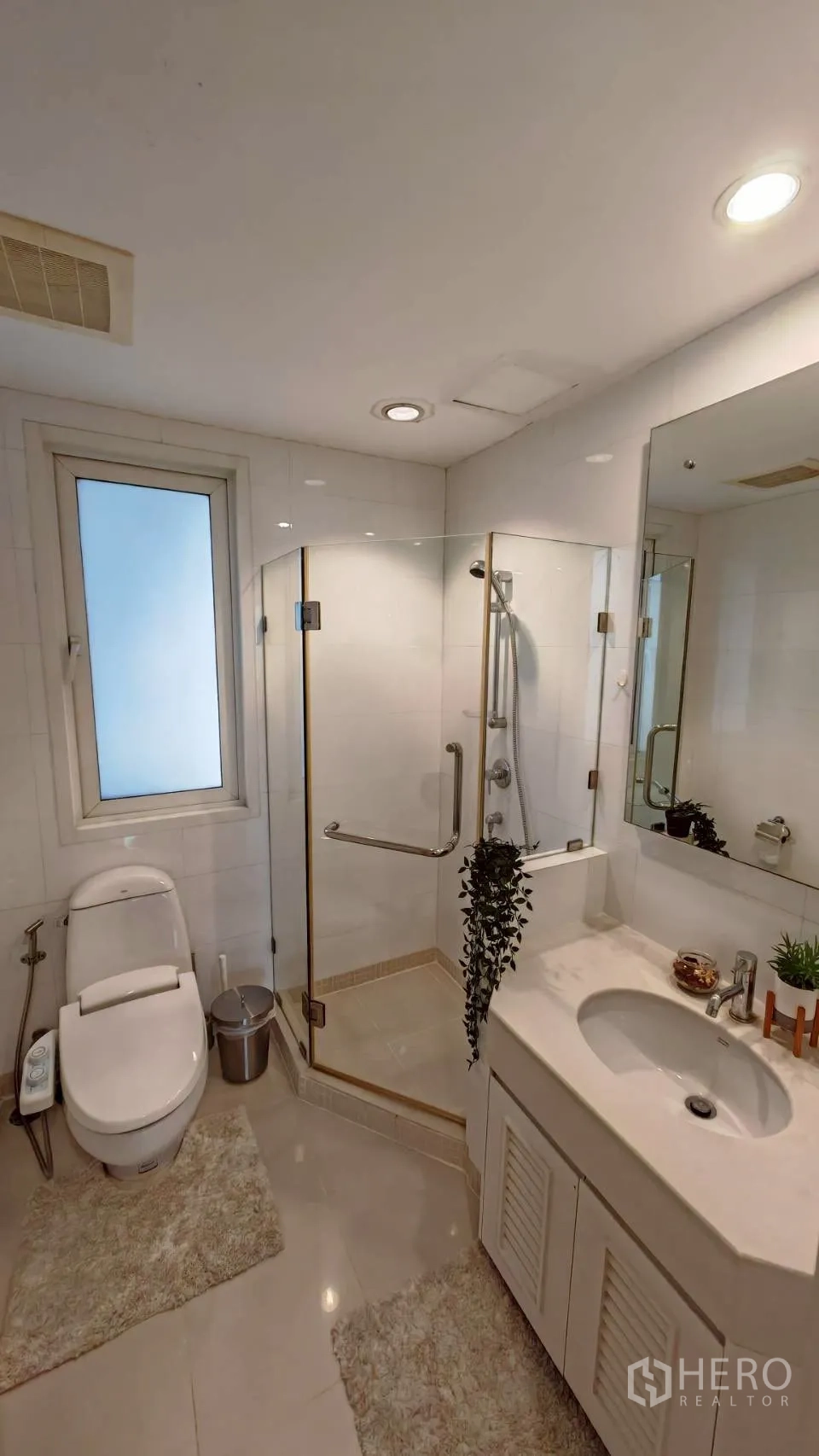 Condominium for rent in Khlong Toei, Bangkok - Bright bathroom with glass shower, vanity and a window.