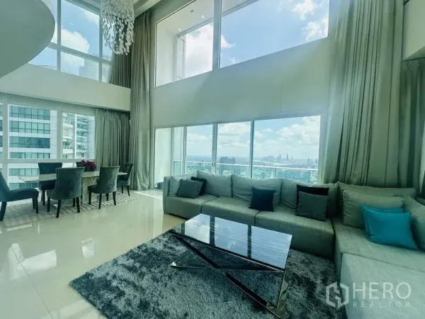 คอนโด ให้เช่าหรือขายในKhlong Toei, Bangkok - ห้องนั่งเล่นเพนท์เฮาส์ดูเพล็กซ์ที่ Millennium Residence เพดานสูงโปร่ง ผนังกระจกเต็มบาน พร้อมโซฟาและโต๊ะทานข้าว มองเห็นวิวสวนเบญจกิตติและสกายไลน์กรุงเทพฯ