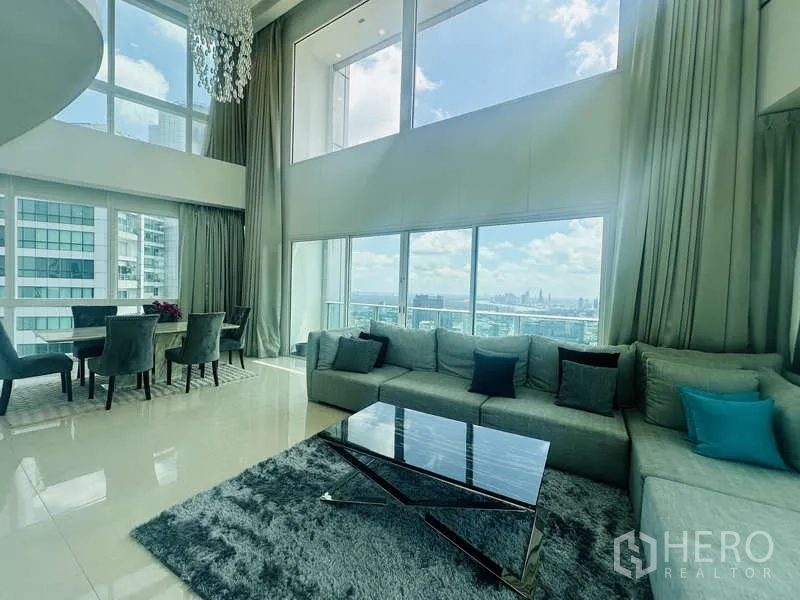 คอนโด ให้เช่าหรือขายในKhlong Toei, Bangkok - ห้องนั่งเล่นเพนท์เฮาส์ดูเพล็กซ์ที่ Millennium Residence เพดานสูงโปร่ง ผนังกระจกเต็มบาน พร้อมโซฟาและโต๊ะทานข้าว มองเห็นวิวสวนเบญจกิตติและสกายไลน์กรุงเทพฯ
