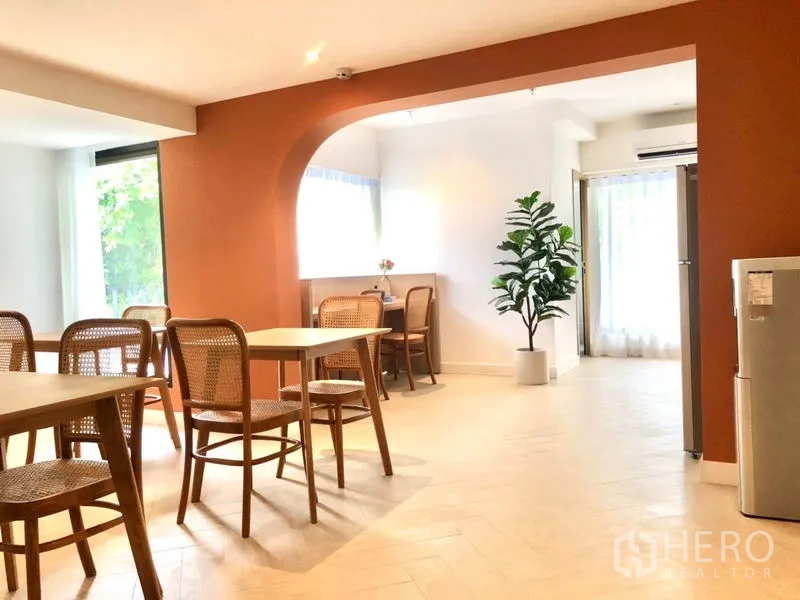 Office Space for rent in Khlong Toei, Bangkok - Open-plan lounge with terracotta arch, cafe-style seating, large windows and potted greenery.