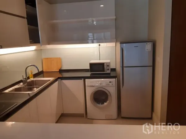 คอนโด ให้เช่าในKhlong Toei, Bangkok - ครัวรูปตัวแอล เคาน์เตอร์ท็อปสีดำ อ่างล้างจานคู่ เครื่องซักผ้า ไมโครเวฟ และตู้เย็น