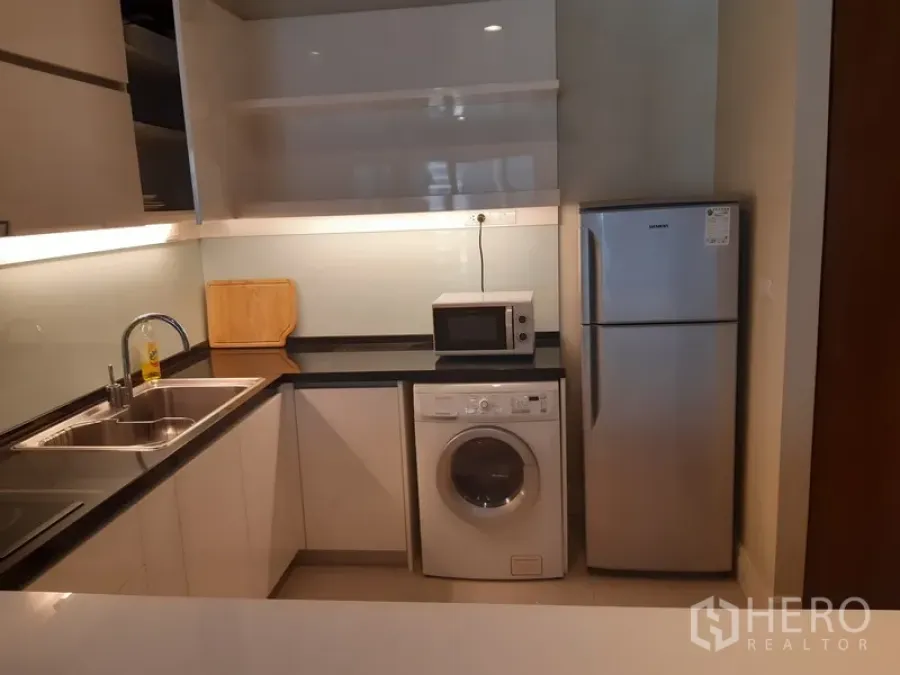 คอนโด ให้เช่าในKhlong Toei, Bangkok - ครัวรูปตัวแอล เคาน์เตอร์ท็อปสีดำ อ่างล้างจานคู่ เครื่องซักผ้า ไมโครเวฟ และตู้เย็น