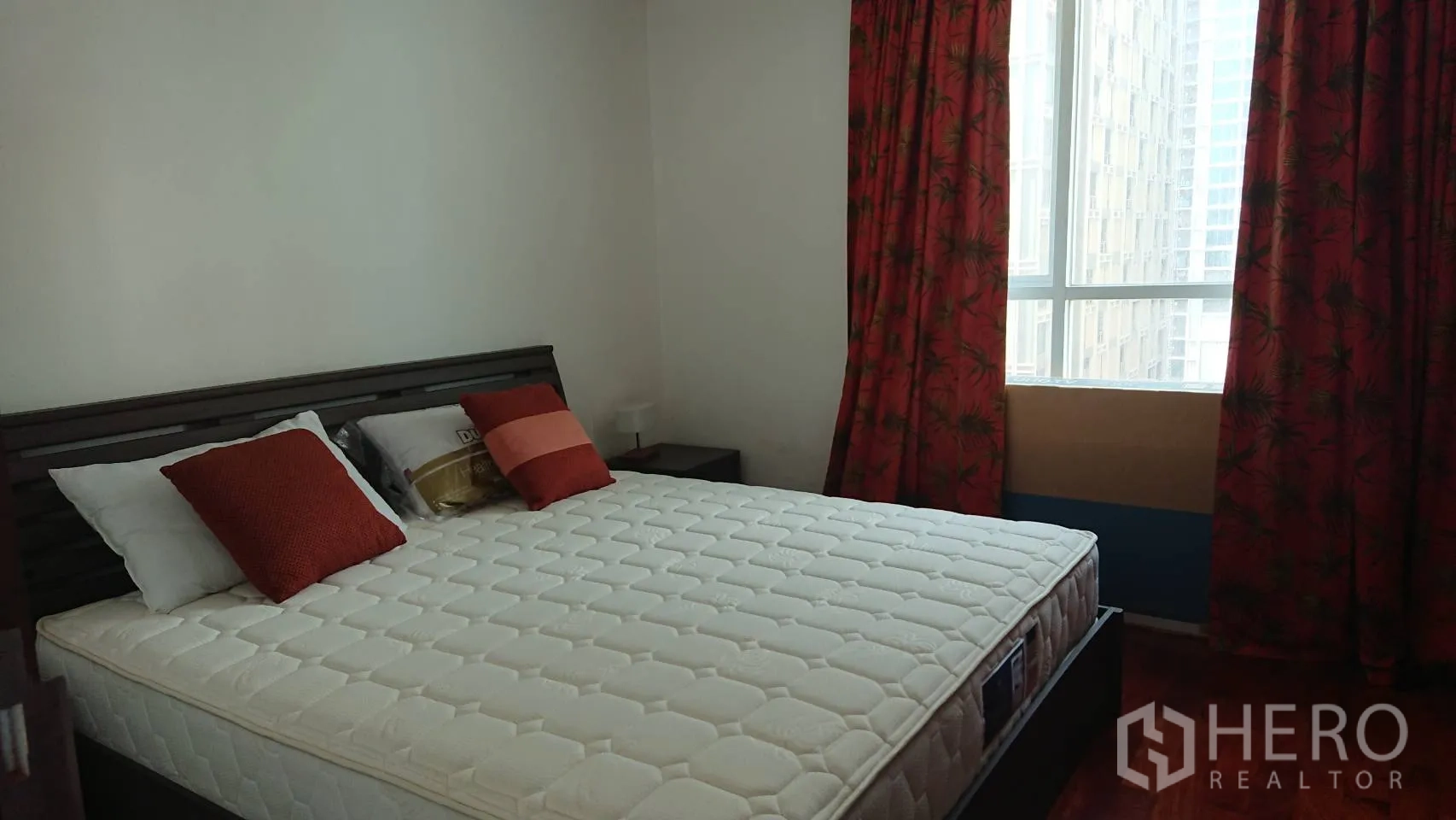 Condominium for rent in Pathum Wan, Bangkok - Second bedroom featuring a double bed, red curtains and natural light from a tall window.