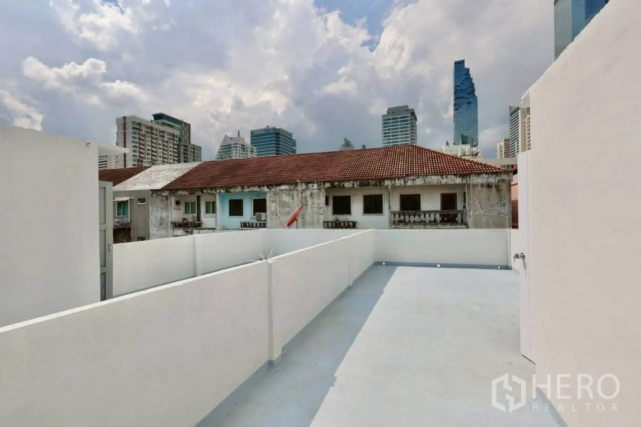 Shophouse for rent in Sathon, Bangkok - Rooftop area facing low-rise neighbors and city towers in the distance.