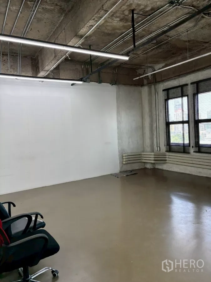 Office Space for rent in Watthana, Bangkok - Work zone with large windows, white feature wall and suspended linear LED light fixtures.