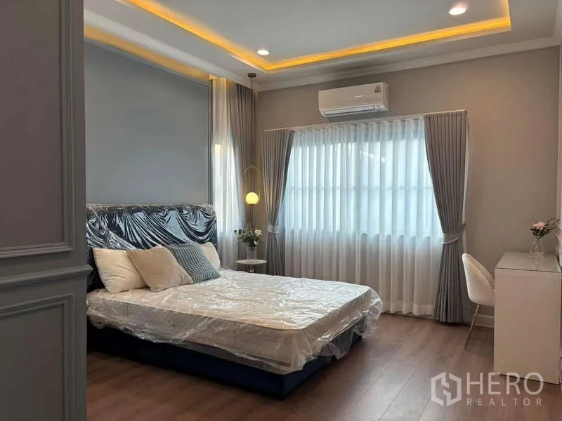Detached House for rent in Bang Phli, Samut Prakan - Guest bedroom with king bed, soft ceiling lighting and study desk by the window.