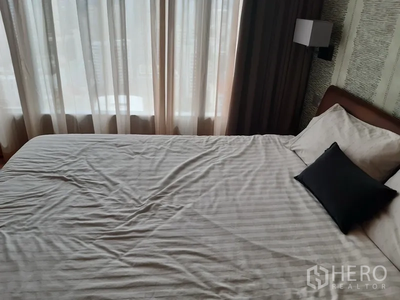Condominium for rent or sale in Watthana, Bangkok - Bedroom with large window, sheer drapes and crisp white bedding.
