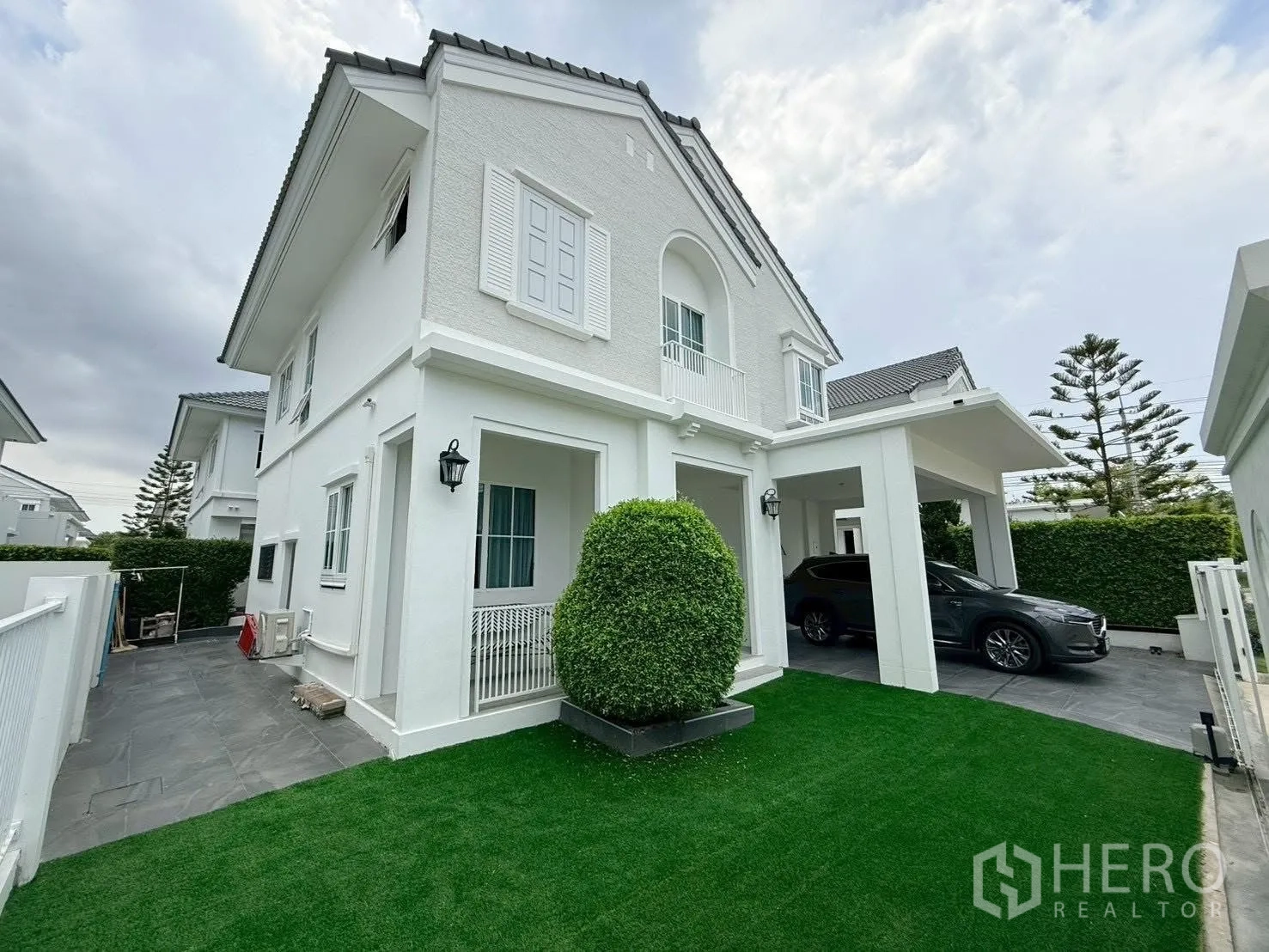 Detached House for rent in Bang Phli, Samut Prakan - Side view of the house with green lawn and a covered carport.