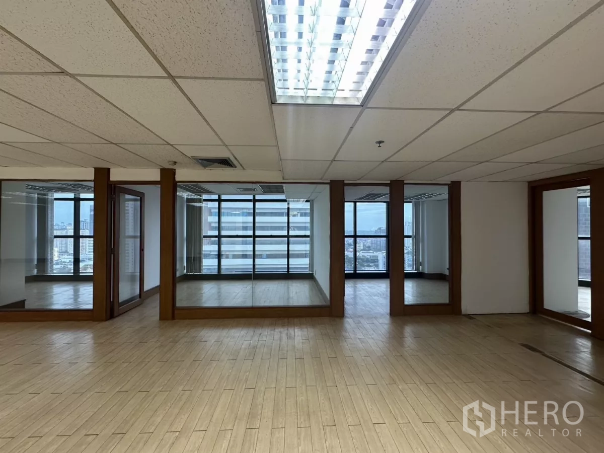 Office Space for rent in Watthana, Bangkok - Row of glass-partitioned rooms and central lighting in a bright office interior.