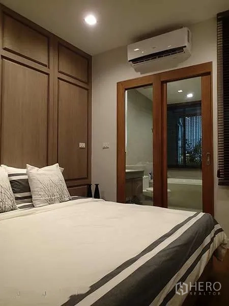 Townhouse for rent in Watthana, Bangkok - Bedroom with built-in wardrobe, air conditioner, and sliding door to ensuite.