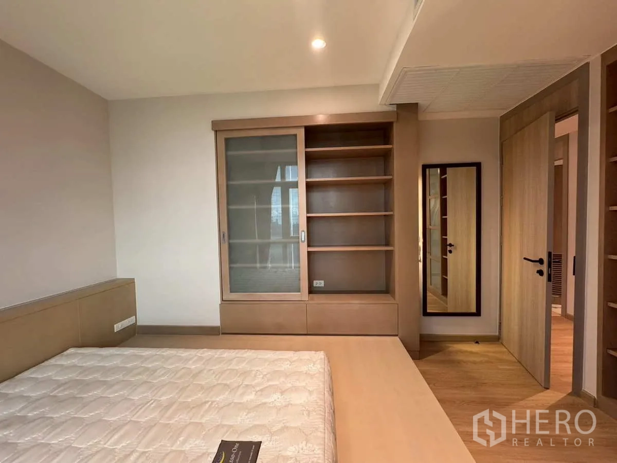 Condominium for rent or sale in Khlong Toei, Bangkok - Bedroom storage with built-in shelves, sliding wardrobe and full-length mirror.
