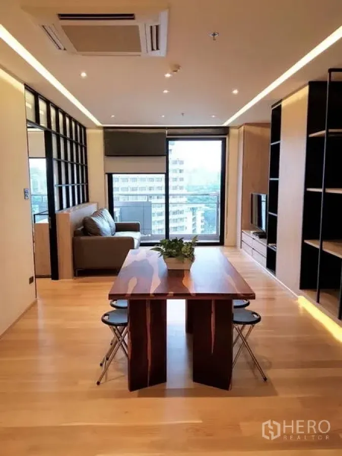 Condominium for rent in Bang Rak, Bangkok - Dining zone centered in an airy open-plan room with wood floors and a city outlook.