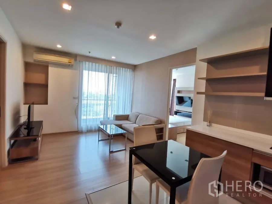 公寓 出租或出售在Khlong Toei, Bangkok - 餐区与客厅一体，通向阳台的落地玻璃门与开放式搁架。