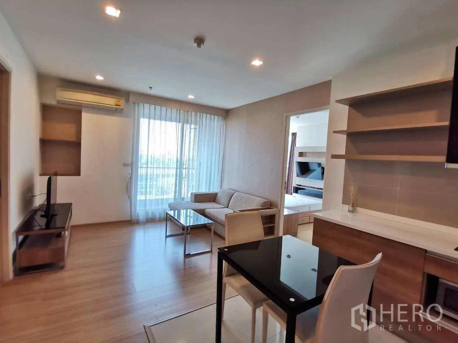 公寓 出租或出售在Khlong Toei, Bangkok - 餐区与客厅一体，通向阳台的落地玻璃门与开放式搁架。