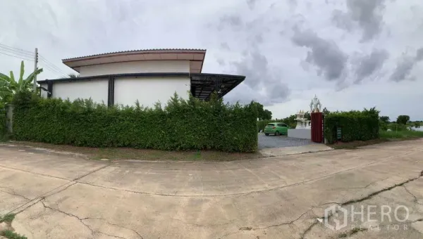 工厂 出售在Bang Pa-in, Phra Nakhon Si Ayutthaya - 街景全景：高绿篱遮挡的工厂，带大门与宽敞车道。