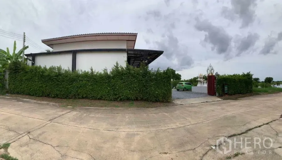 工厂 出售在Bang Pa-in, Phra Nakhon Si Ayutthaya - 街景全景：高绿篱遮挡的工厂，带大门与宽敞车道。