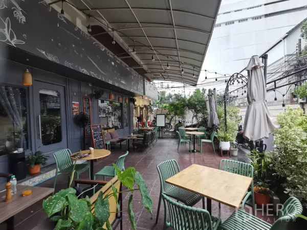 零售空间 出租在Watthana, Bangkok - 带顶棚的露台就餐区，串灯、绿化与咖啡桌。