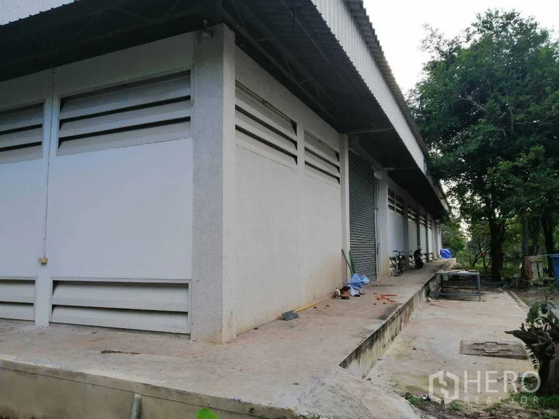 Factory for rent in Pathum Thani - Side view of the warehouse showing a raised loading platform, louvered vents and metal roller shutters.
