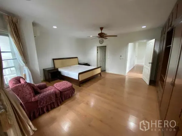 联排别墅 出租或出售在Mueang Samut Prakan, Samut Prakan - 主卧另一角度，躺椅、壁柜与木地板。