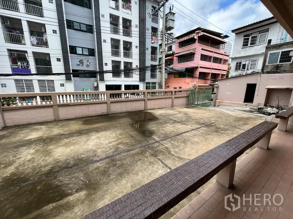 独立式住宅 出租在Suan Luang, Bangkok - 前庭与停车区域，低围墙及周边城市建筑