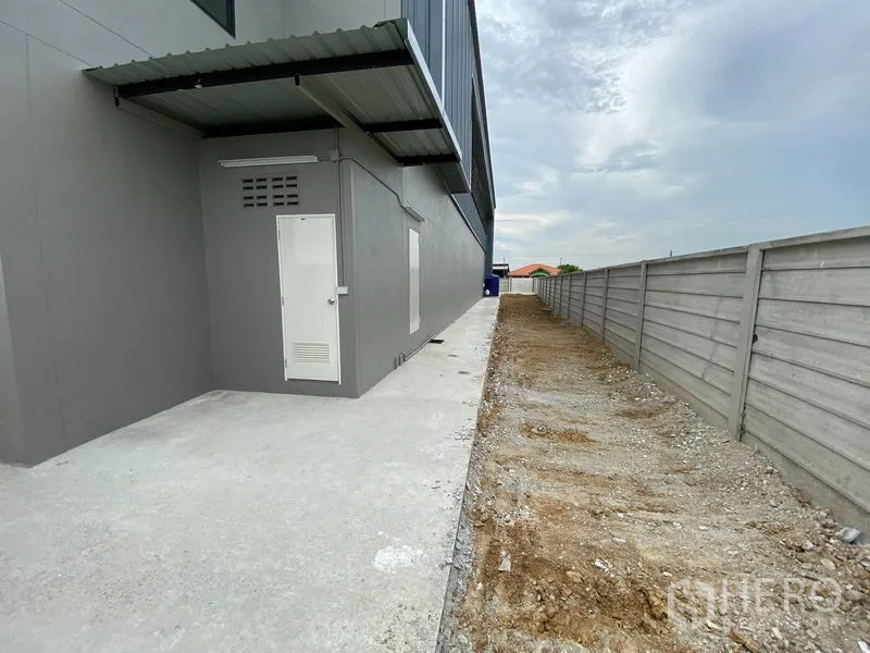 Warehouse for rent or sale in Bang Len, Nakhon Pathom - Side walkway with utility door along the warehouse and boundary wall.