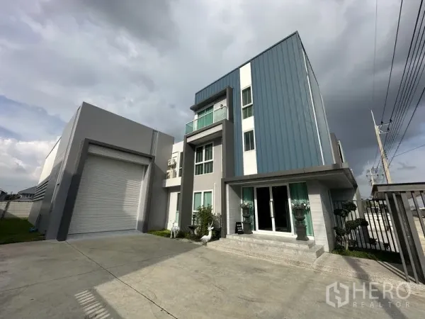Factory for sale in Lam Luk Ka, Pathum Thani - Front driveway showing warehouse loading bay with roller shutter beside the three-storey office.