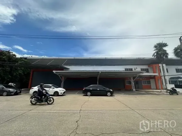 工厂 出租在Nonthaburi - 工厂正面展示带顶装卸区与充足的前场停车空间。