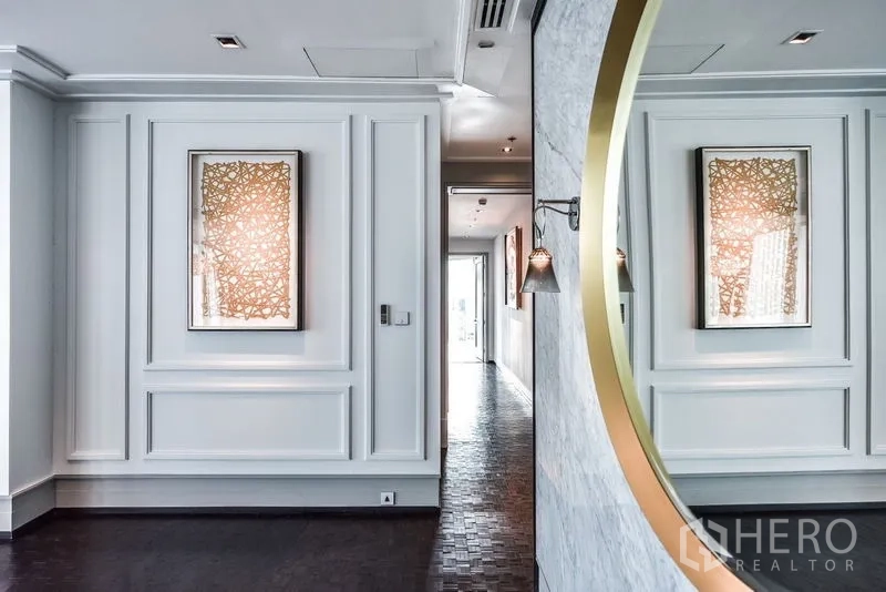 公寓 出租在Bang Rak, Bangkok - 优雅走廊，墙面线条装饰、圆形镜与壁灯。