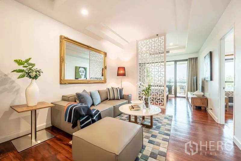 คอนโด ให้เช่าหรือขายในKhlong San, Bangkok - มุมนั่งเล่นพร้อมโซฟาตัวแอล อ็อตโตมัน กระจกบานใหญ่ และฉากลาย ใกล้ระเบียง