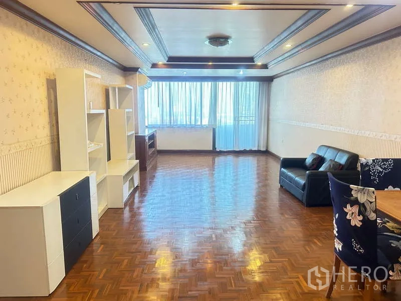 Condominium for sale in Huai Khwang, Bangkok - Wide living area with sofa, open shelving, dining set, and floor-to-ceiling windows.