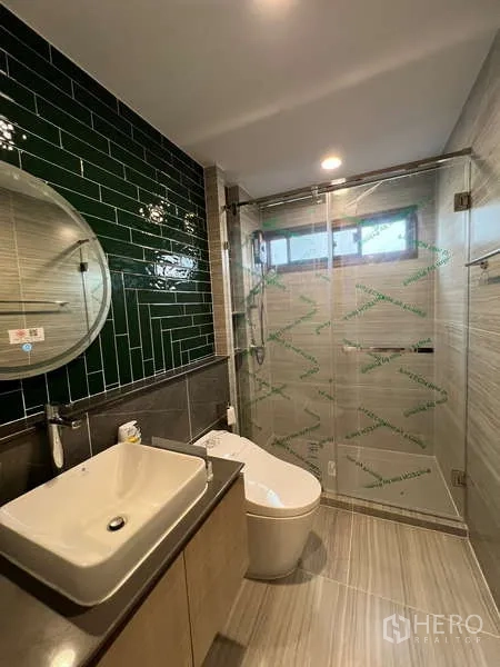 บ้าน ให้เช่าในBang Kapi, Bangkok - ห้องน้ำพร้อมกระจกกลม อ่างล้างหน้าวางบนเคาน์เตอร์ และผนังกระเบื้องสีเขียว