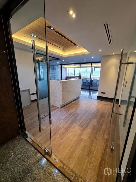 办公空间 出租在Bang Rak, Bangkok - 入口双开玻璃门，通向灯光温暖的接待区。