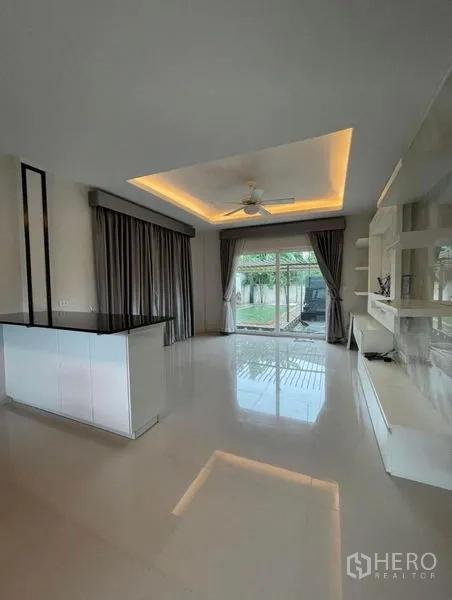 独立式住宅 出售在Bang Phli, Samut Prakan - 客厅以推拉门连通花园，阶梯天花与定制电视柜。