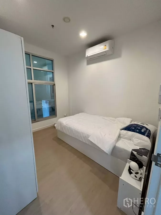 公寓 出租在Bang Rak, Bangkok - 第二卧室配单人床、空调与室内玻璃窗，极简风格。