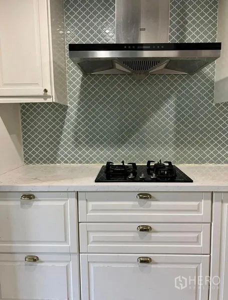 Townhouse for rent or sale in Bueng Kum, Bangkok - Kitchen gas cooktop with stainless hood and patterned mosaic backsplash.