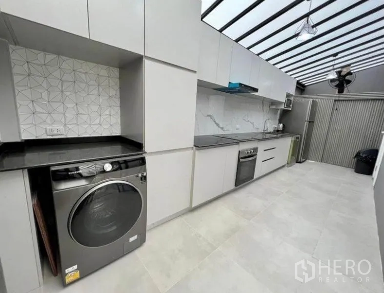 ทาวน์เฮาส์ ให้เช่าในWang Thonglang, Bangkok - มุมมองที่สองของครัว พร้อมเตา เครื่องซักผ้า และตู้เก็บของบิวท์อิน