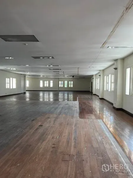 Office Space for rent in Khlong Toei, Bangkok - Long office hall with mixed-tone hardwood floors, multiple windows, and ceiling light panels across an open workspace.