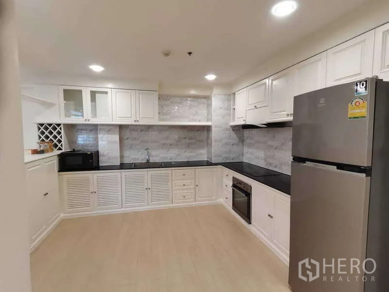 อพาร์ทเมนท์ ให้เช่า - ครัวบิวท์อินตู้สีขาว ท็อปสีดำ พร้อมตู้เย็นสแตนเลส