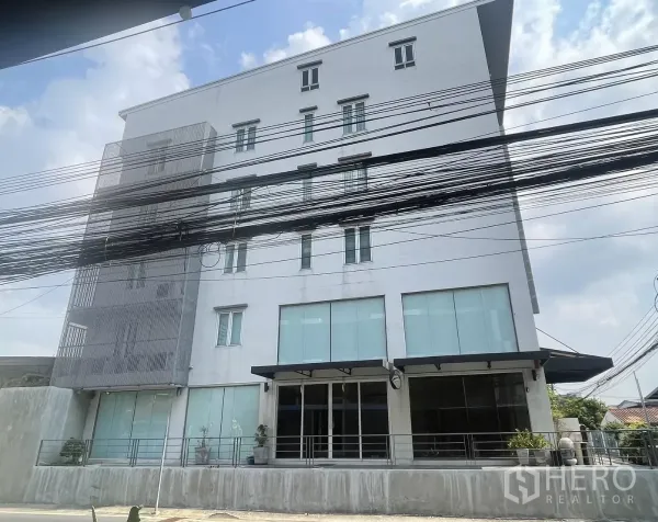 Home Office for rent in Suan Luang, Bangkok - Front elevation of a white office building featuring large tinted windows and balcony details.