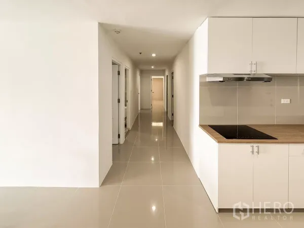 公寓 出租在Khlong Toei, Bangkok - 长走廊带简洁小厨房，亮面地砖与筒灯。