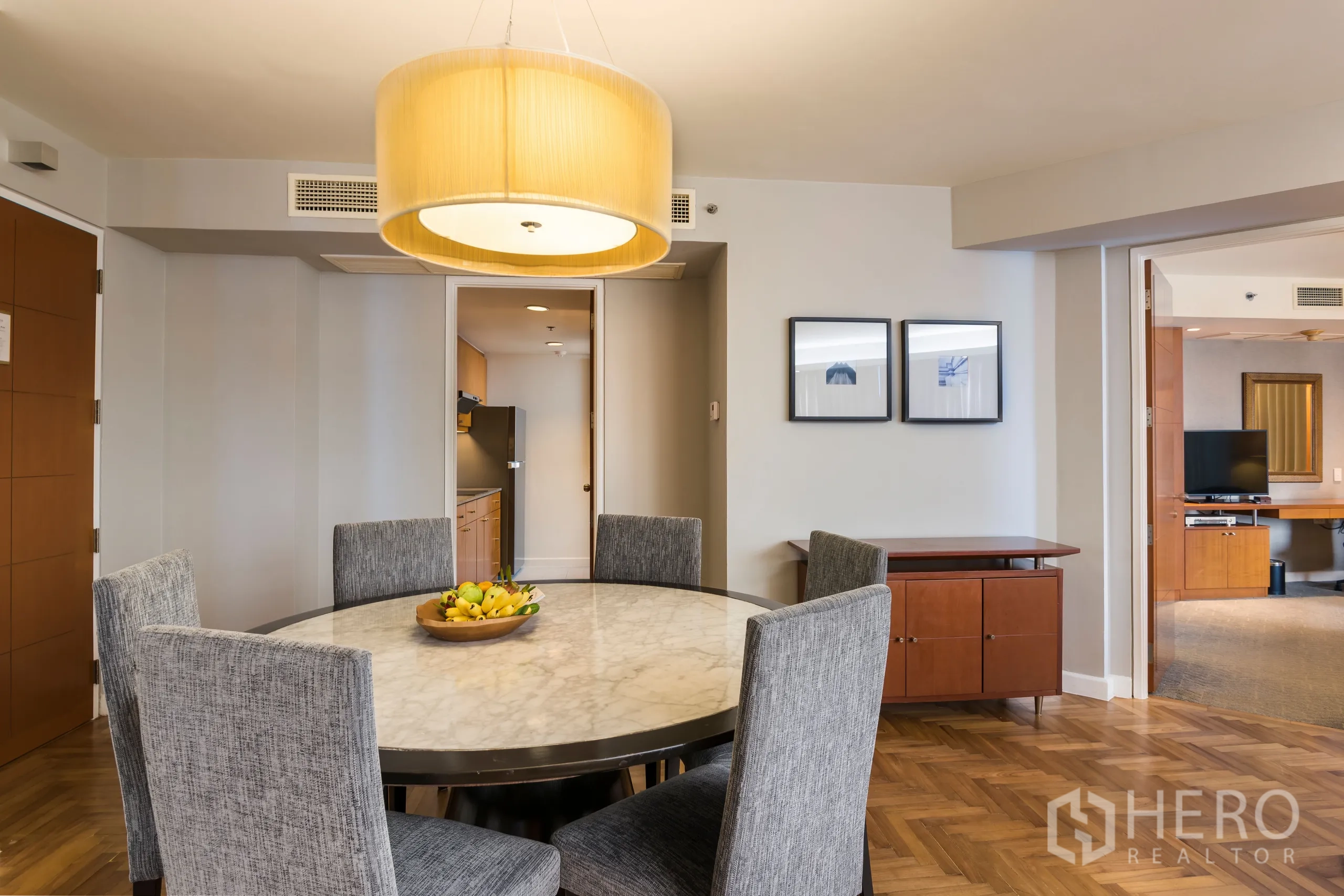 Condominium for rent in Yan Nawa, Bangkok - Dining area close-up with six upholstered chairs around a round marble table under a pendant light.