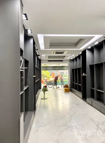 零售空间 出租在Khlong Toei, Bangkok - 从店内望向街道的长型通道，天花嵌入式空调与两侧展示柜。